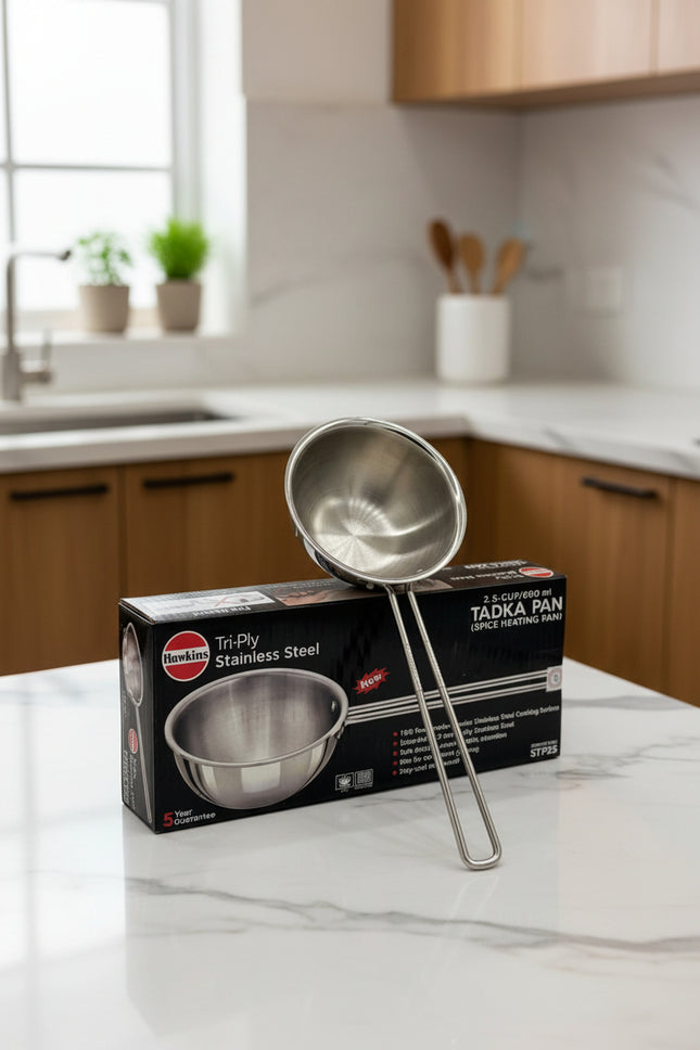 Stainless steel Tadka pan with its packaging on a gray background